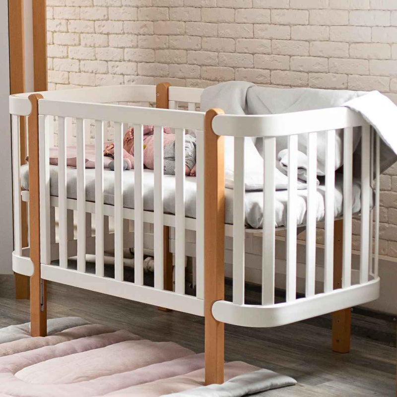 Lettino affiancabile per neonati Zukko Gekko 120x60. Evolutivo – con funzione di trasformazione disponibile. Può essere dotato di ruote o di meccanismo a dondolo per la nanna. Colore: Bianco – Faggio Naturale.